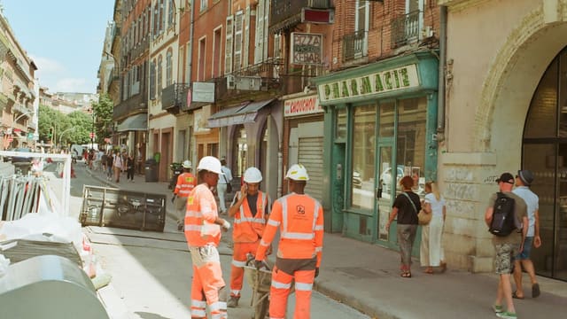 a group of construction workers standing on the side of a road