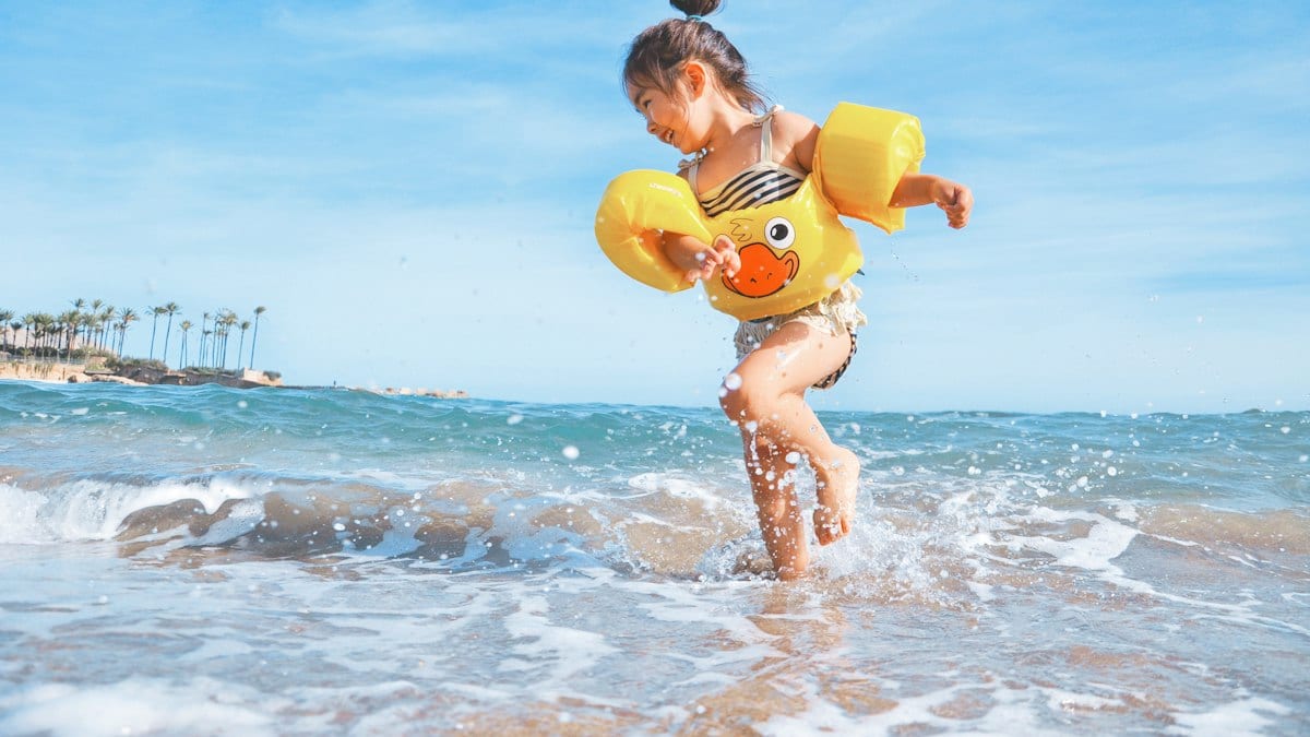 girl playing beside body of water during daytime