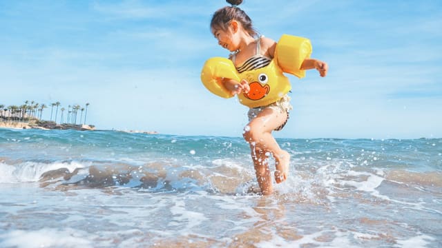 girl playing beside body of water during daytime
