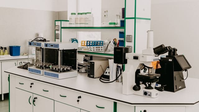 A laboratory workbench with a microscope and analytical equipment in a bright room