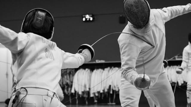 a couple of people that are standing up with fencing equipment