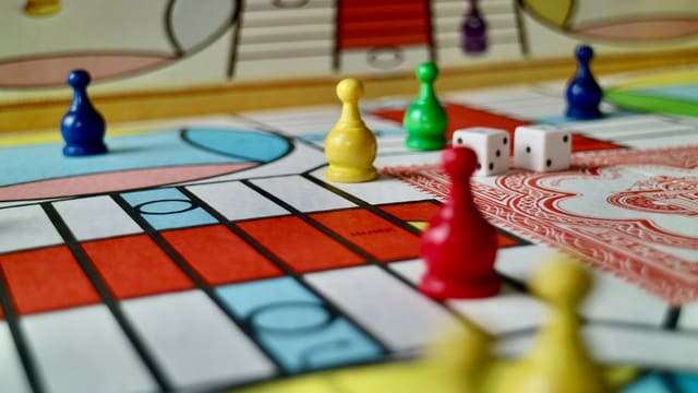 Colorful plastic game pieces and two white dice on a board game