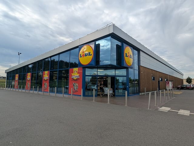 Devanture vitrée d'un magasin Lidl, logo jaune et rouge au-dessus de l'entrée.