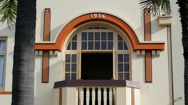 a tall white building with a window and a balcony