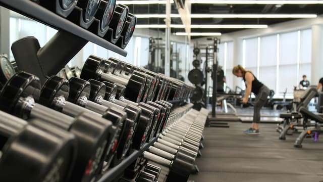 woman standing surrounded by exercise equipment