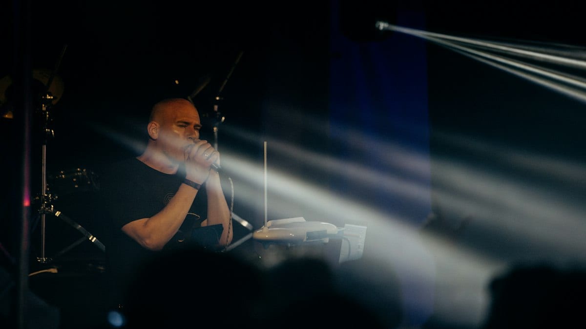 A man performing on stage with instruments and spotlights