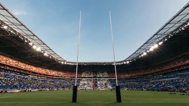 Rugby goal posts on a green field inside a large crowded stadium