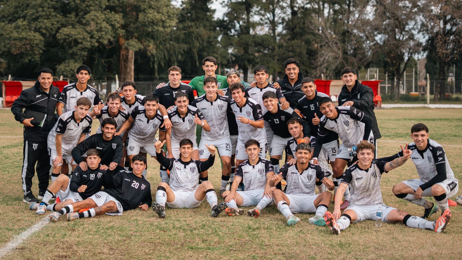 Youth soccer team posing on field after a victorious match, displaying team spirit.
