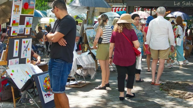 People browse art at an outdoor market.